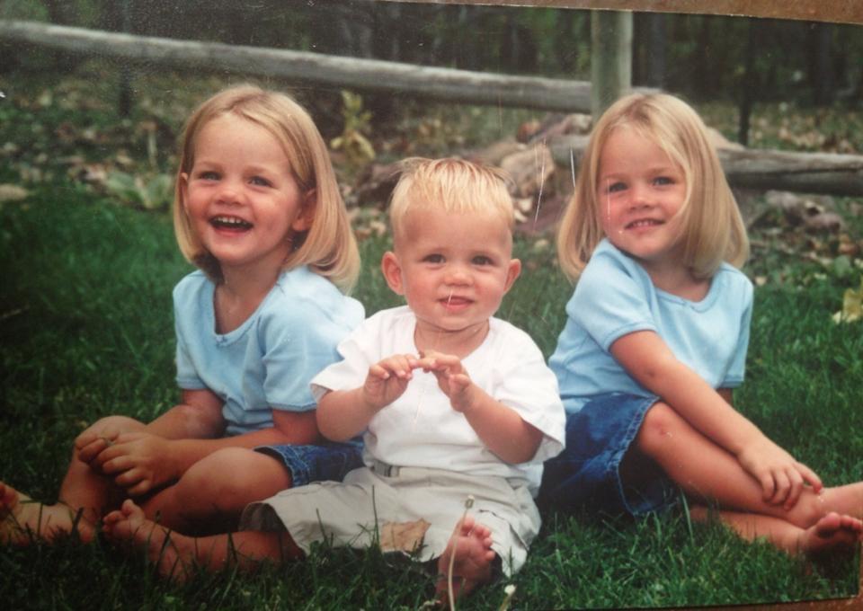 Baby Isaiah Hudgens sitting on the grass between his two older sisters