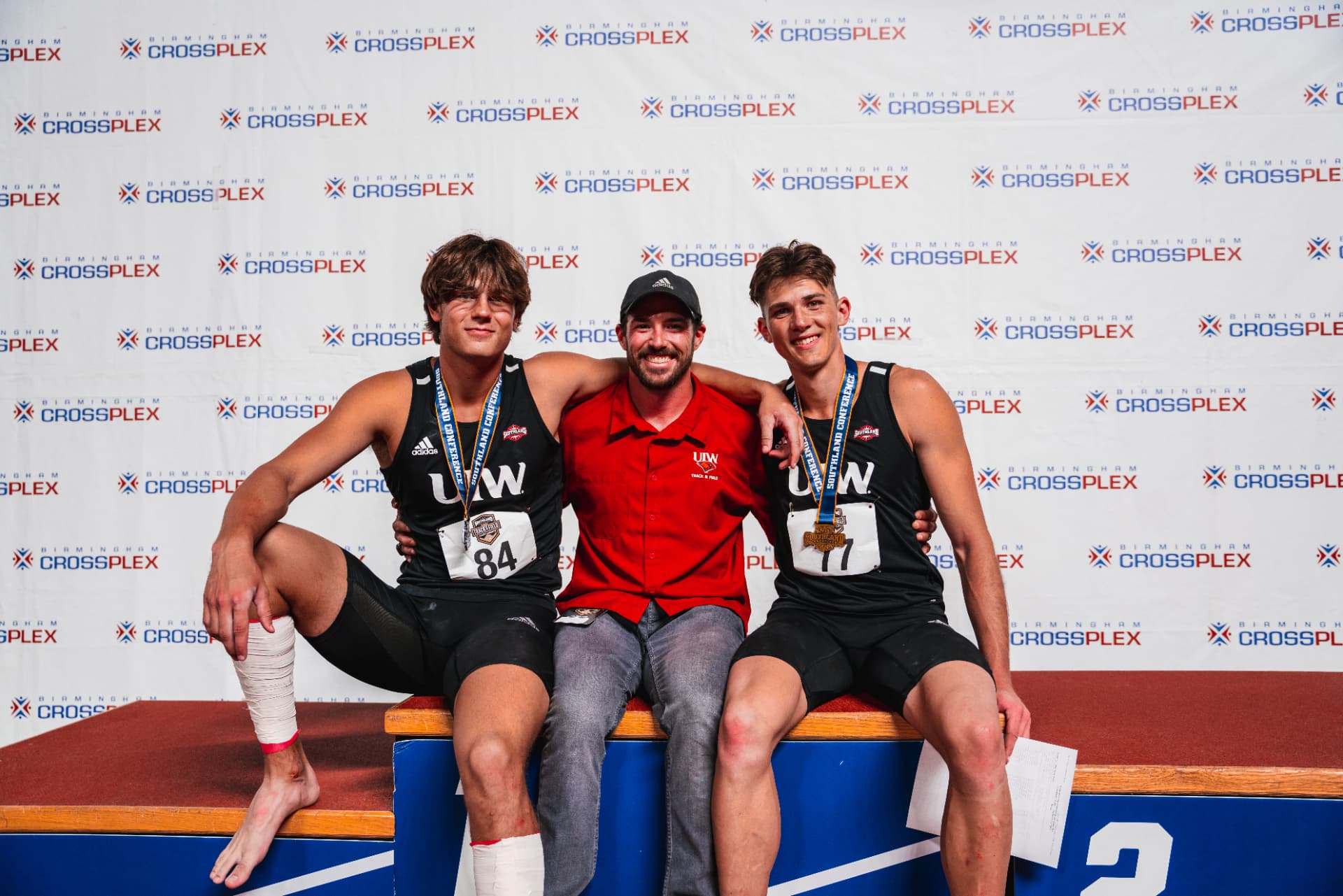 Isaiah Hudgens on the podium with his coach and teammate at the Southland Conference Indoor Championships, Birmingham CrossPlex