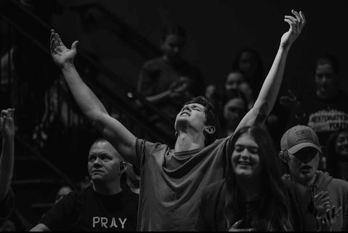 Isaiah Hudgens with his arms raised in worship at church